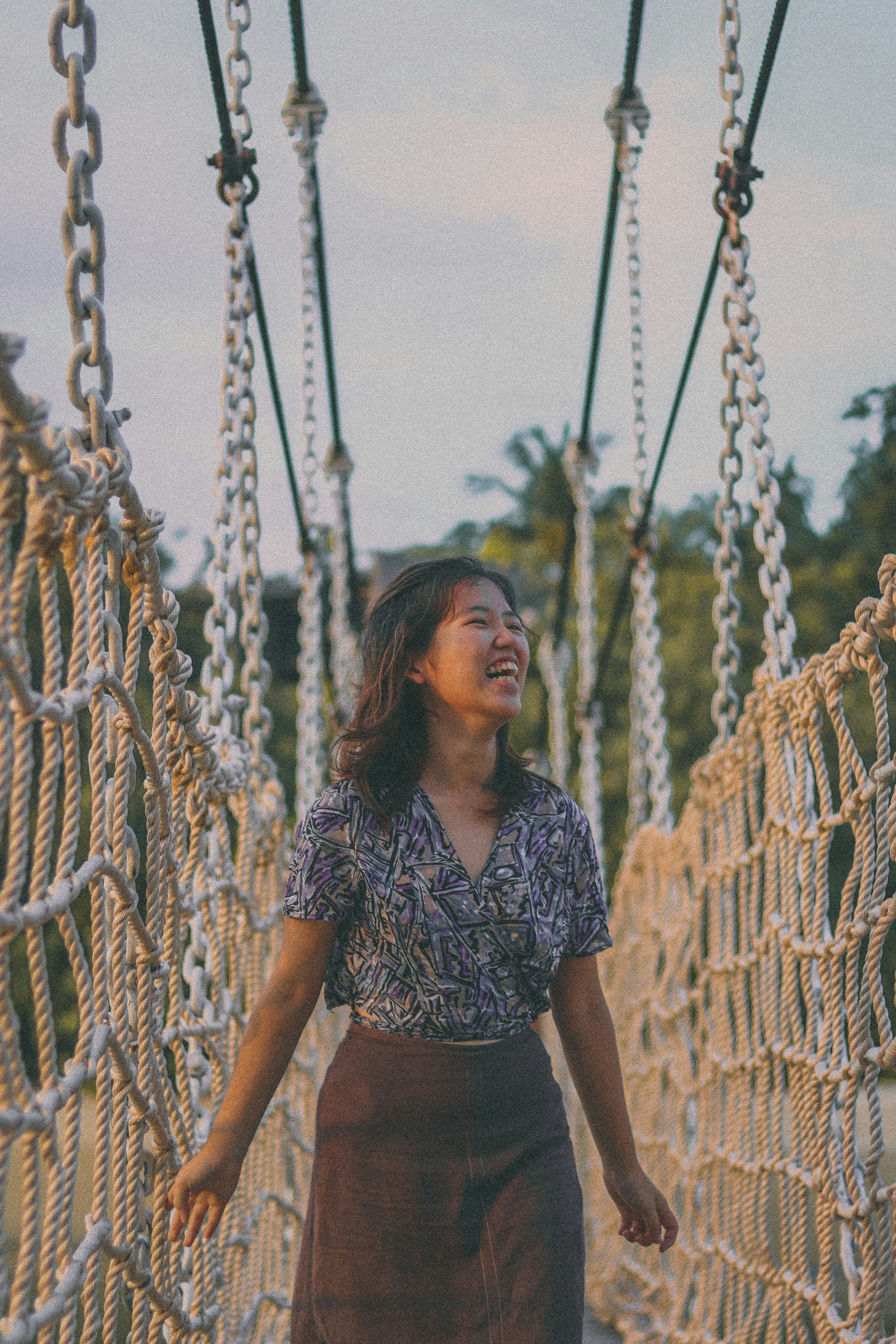 woman in black and white floral shirt standing beside brown wooden fence during daytime